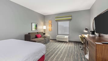 Une chambre d’hôtel avec un lit, un bureau, une chaise, une télévision et une fenêtre.