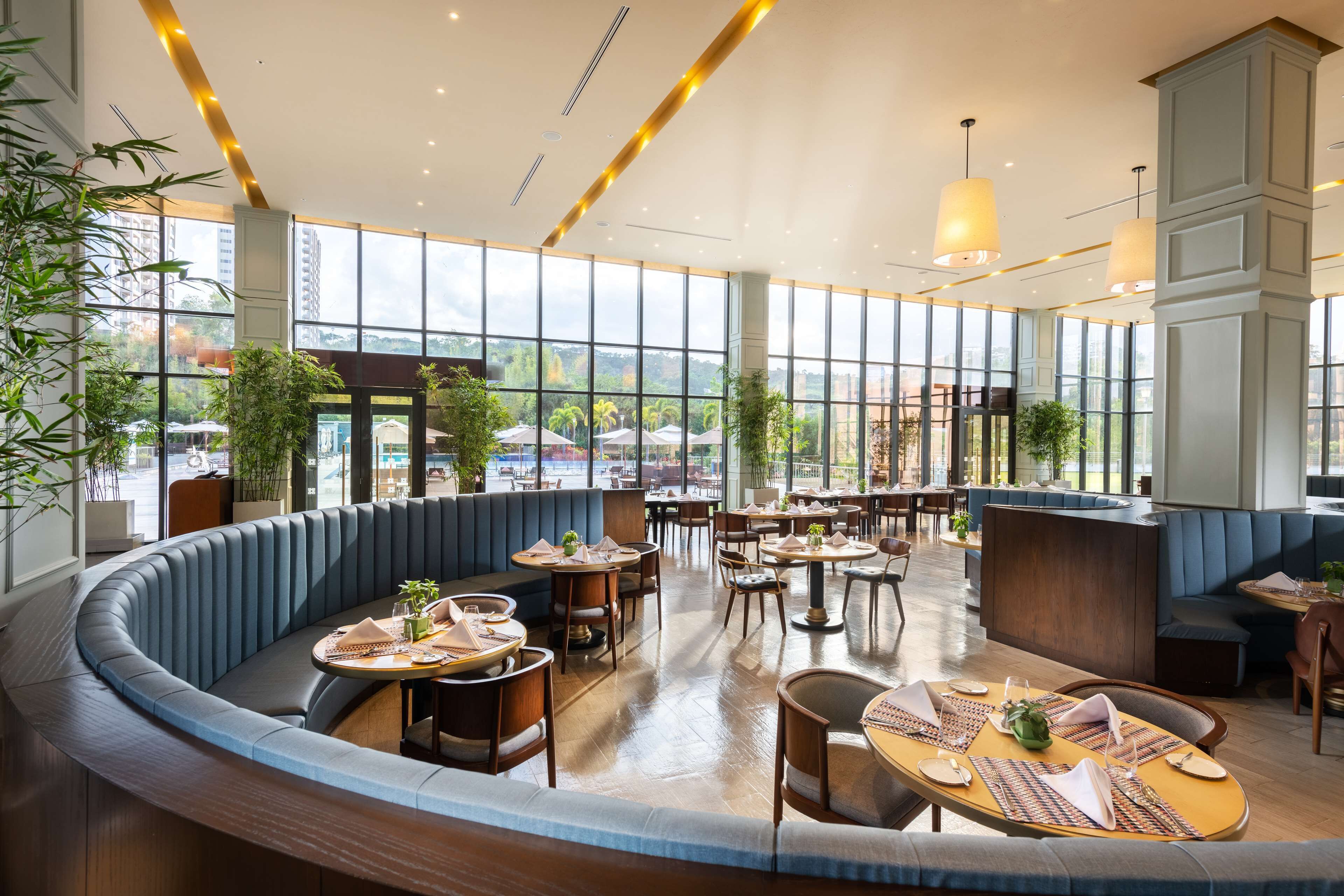 A modern restaurant with a curved seating area, large windows, and indoor plants.