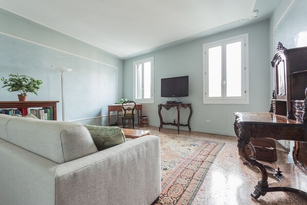 A living room with a sofa, a television, a wooden table, and a patterned rug.