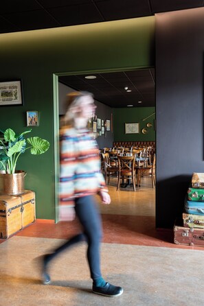 Une personne se promène dans un restaurant dont les murs sont peints en vert et dont le mobilier est en bois.