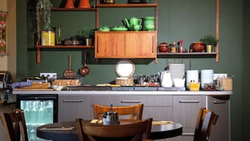 Una cocina con armarios de madera, una mesa de comedor, sillas y varios utensilios y electrodomésticos.