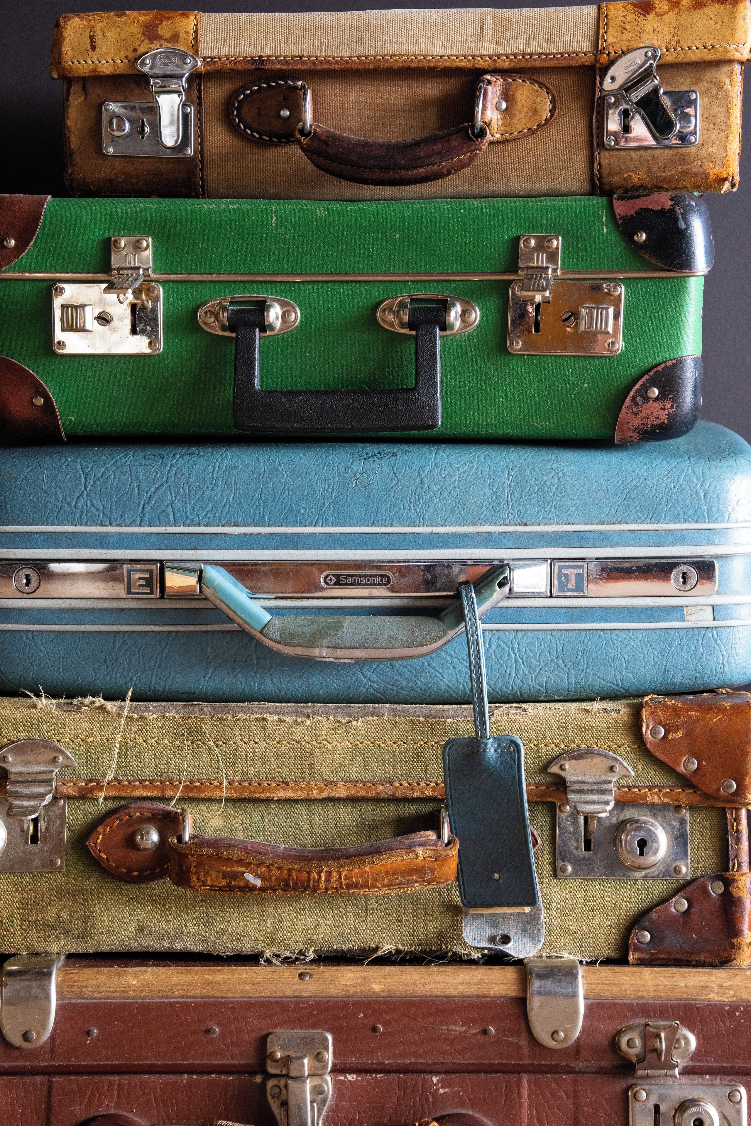 A stack of vintage suitcases with metal clasps and leather straps.