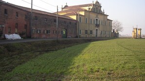 A building with a large green door, a brick facade, and a yellow building across the street. - B&B Ca' Gialla (Urbana)