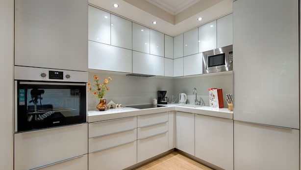 A modern kitchen with white cabinets, a built-in oven, a microwave, and a coffee maker. - Apartment Marella (Split)