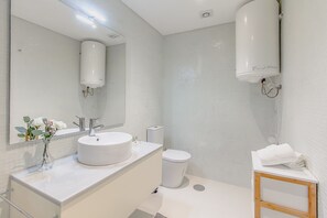 Ein modernes Badezimmer mit Waschbecken, Spiegel und Toilette in Weiß.