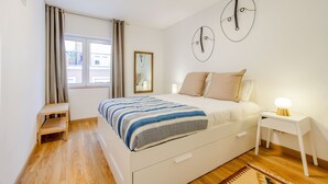 A bedroom with a bed, bedside table, and a window with curtains.
