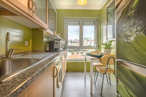 A compact kitchen with a sink, stove, and a window overlooking a cityscape.