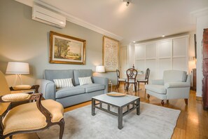 A living room with a sofa, armchairs, a coffee table, and a dining area with chairs and a table.