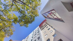 Een hoog gebouw met veel ramen en een rode vluchttrap.