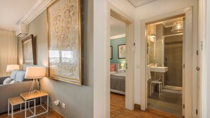Een moderne zithoek met een bank, een bijzettafeltje met een lamp en een groot kunstwerk in een lijst aan de muur.