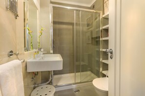 A bathroom with a glass-enclosed shower, a white sink, and a toilet.