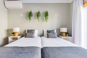 Una cama doble con dos mesitas de noche, cada una con una lámpara y una planta pequeña.