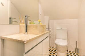 A bathroom with a marble sink, a toilet, and a checkered floor. - Steps Lisbon @ Historical Center (Lisbon)