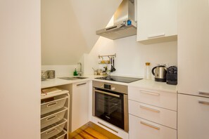 A compact kitchen with white cabinets, a Bosch oven, a kettle, and a sink.