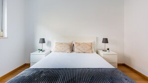 Ein schlicht eingerichtetes Schlafzimmer mit einem großen Bett, zwei Nachttischen und einem Fenster.