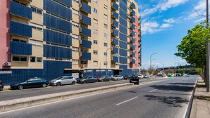 Ein mehrstöckiges Gebäude mit Balkonen, einem Parkplatz und blauem Himmel.