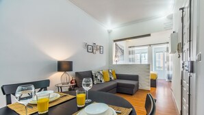 A modern dining area with a round table set for two, featuring a glass of orange juice and a wine glass. - Paraíso Alfama (Lisbon)