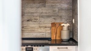 A kitchen with a wooden backsplash, a stainless steel oven, and a white cabinet. - Paraíso Alfama (Lisbon)