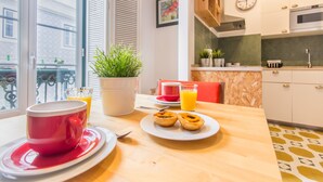 A breakfast table with a red mug, two plates of pastries, a glass of orange juice, and a potted plant. - São Vicente Heart of Alfama (Lisbon)