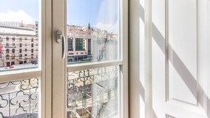 Vista da una finestra con ringhiera in metallo su un paesaggio urbano con edifici e cielo sereno.