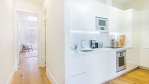 Una cucina moderna con mobili bianchi, forno integrato e microonde.