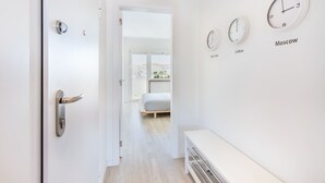A hallway with a bed, a bench, and wall clocks labeled with city names. - Graça Amazing River Views (Lisbon)