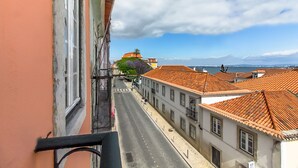 Una vista di strada con edifici, cielo sereno e una lontana visuale del mare.