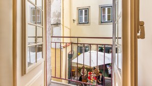 Un balcone con vista su una scena di strada, che include un negozio con un ombrello.