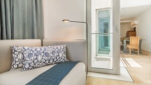 A modern living room with a sofa, patterned pillow, and a floor lamp. - Luxury Beach Experience in Lisbon (Oeiras)