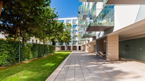A modern building with a tiled pathway, greenery, and a clear sky. - Luxury Beach Experience in Lisbon (Oeiras)