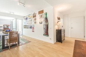 A modern kitchen with a dining area, featuring a large wall of various decorative items and a prominent Coca-Cola bottle. - Luxury Beach Experience in Lisbon (Oeiras)