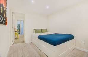 Un dormitorio con una cama, una puerta que da a un balcón y una silla amarilla.