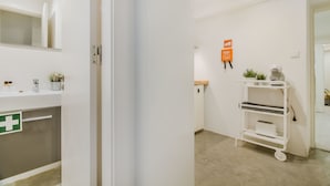 A clean, modern bathroom with a white sink, mirror, and a green emergency exit sign.