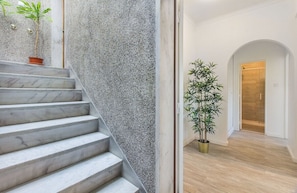 A staircase with marble steps leading to a room with a wooden floor, a potted plant, and a door leading to another room. - Roma Cozy Flat (Lisbon)