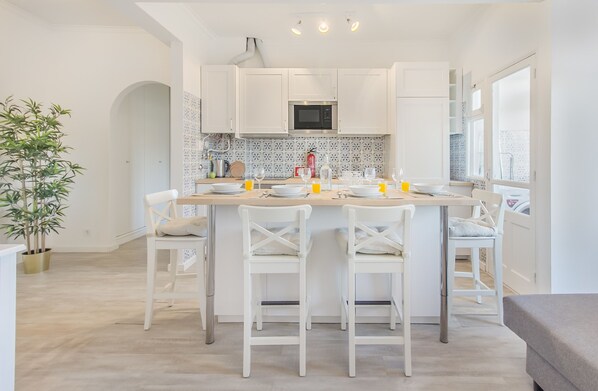 Une cuisine moderne avec des meubles blancs, un îlot central doté de sièges et un revêtement mural décoratif.