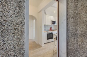 A modern kitchen with white cabinets, a microwave, and an oven. - Roma Cozy Flat (Lisbon)