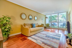 A living room with a beige sofa, a patterned rug, and three wall mirrors. - 347 Acácias Flat (Cascais)