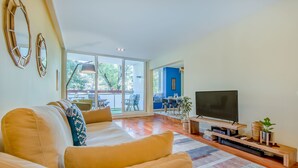 A modern living room with a sofa, TV, and entertainment unit. - 347 Acácias Flat (Cascais)