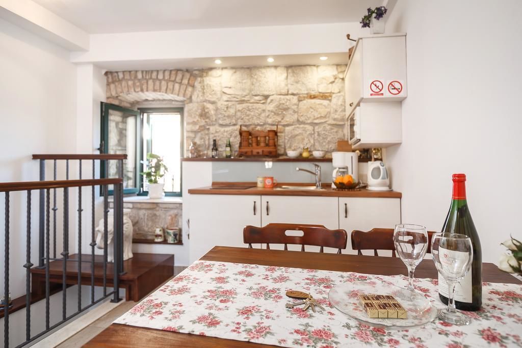 A kitchen with a stone wall, wooden cabinets, and a dining table set with a bottle of wine and glasses.