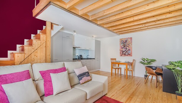 A modern living room with a staircase, a dining area, and a kitchen. - Graça Cozy Duplex (Lisbon)