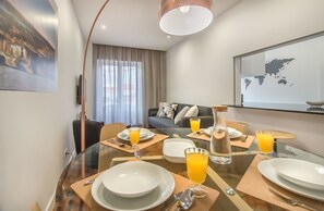 Ein modernes Hotelzimmer mit Frühstückstisch, einer Sitzecke und einer großen Weltkarte an der Wand.