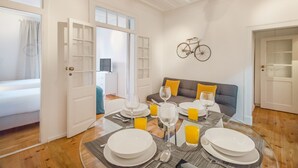 A dining area with a table set for four, surrounded by white walls and a wooden floor. - Lisbon City Stay Largo do Carmo (Lisbon)
