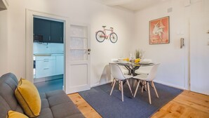 A compact living space with a dining area, a sofa, and a kitchen visible through an open door. - Lisbon City Stay Largo do Carmo (Lisbon)