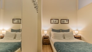 A bedroom with a bed, two bedside tables, a mirror, and framed pictures on the wall. - Correeiros Downtown - Historic Lisbon Apartment (Lisbon)
