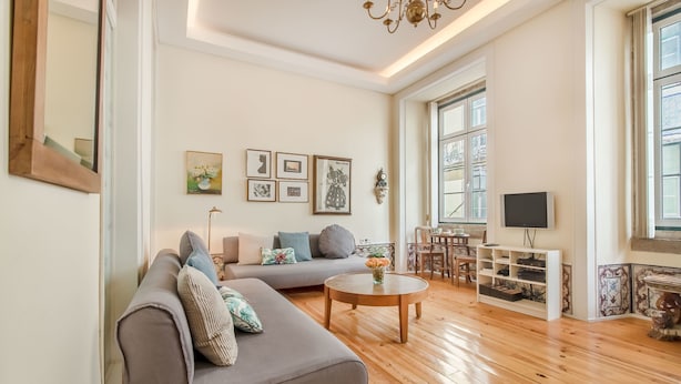 A spacious living room with a grey sofa, wooden coffee table, and a TV on a stand. - Correeiros Downtown - Historic Lisbon Apartment (Lisbon)