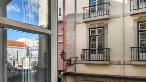 Un immeuble à plusieurs étages doté de balcons, donnant sur la rue, et dont le reflet se voit dans une fenêtre.