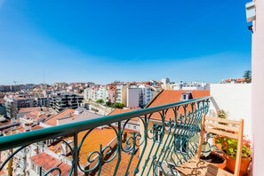 Un balcón con vista a un paisaje urbano, con tejados de tejas rojas y varios edificios.