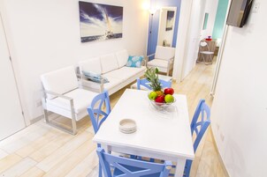Comedor con una mesa blanca, sillas azules y un frutero.