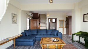 Una sala de estar con un sofá modular, una mesa de centro de madera y una mesita auxiliar verde.