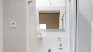 Un baño moderno con lavamanos, espejo y inodoro blancos.